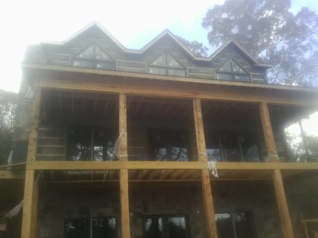 Dormers and porch framing on a large log home under construction — Roof Coating work by our crew in Powder Springs