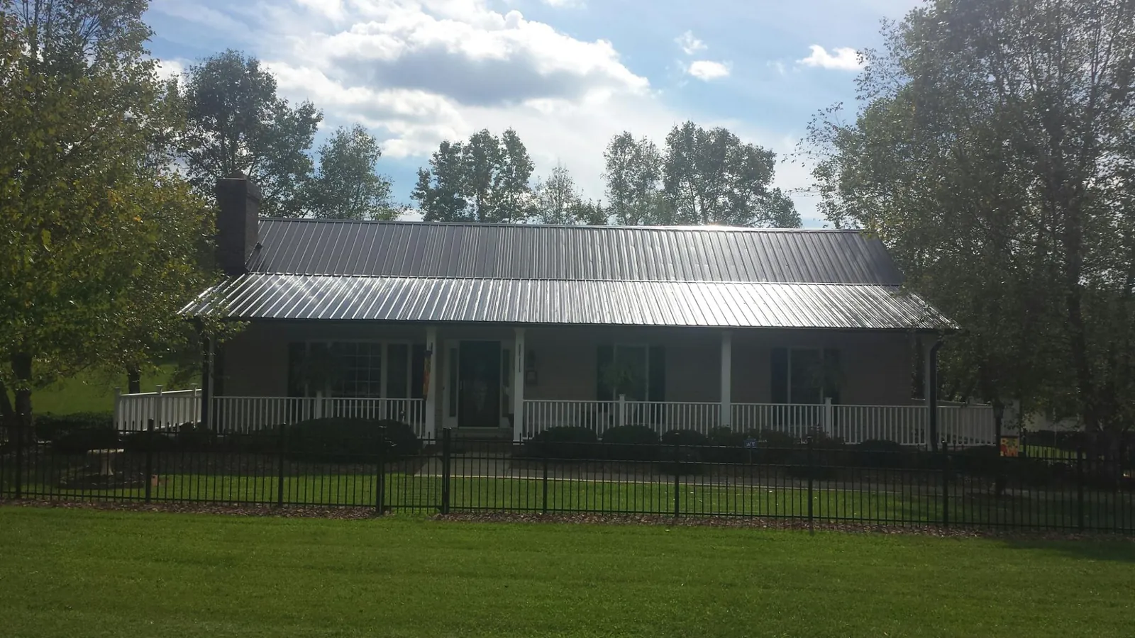 Gray metal roof on a brick ranch with a full width front porch — Gutter Guard Installation work by our crew in Powder Springs