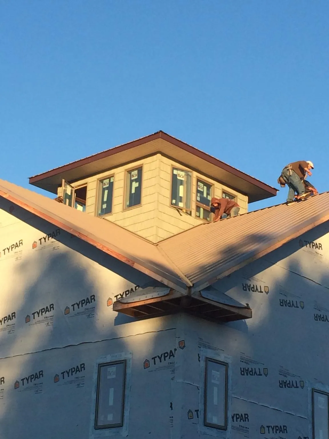 Roofers working around a rooftop cupola on a new metal roof at sunset — Roof Waterproofing in Powder Springs by Roofing Brothers